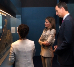 Sus Altezas Reales los Príncipes de Asturias atienden a las explicaciones de la comisaria de la exposición, Susana García